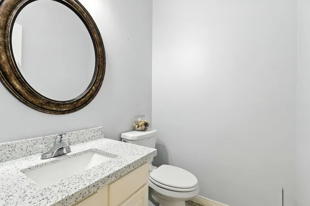 a bathroom with a granite countertop sink a mirror and toilet