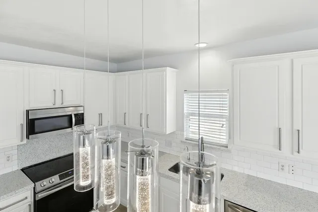 a kitchen with stainless steel appliances white cabinets and a wooden floor