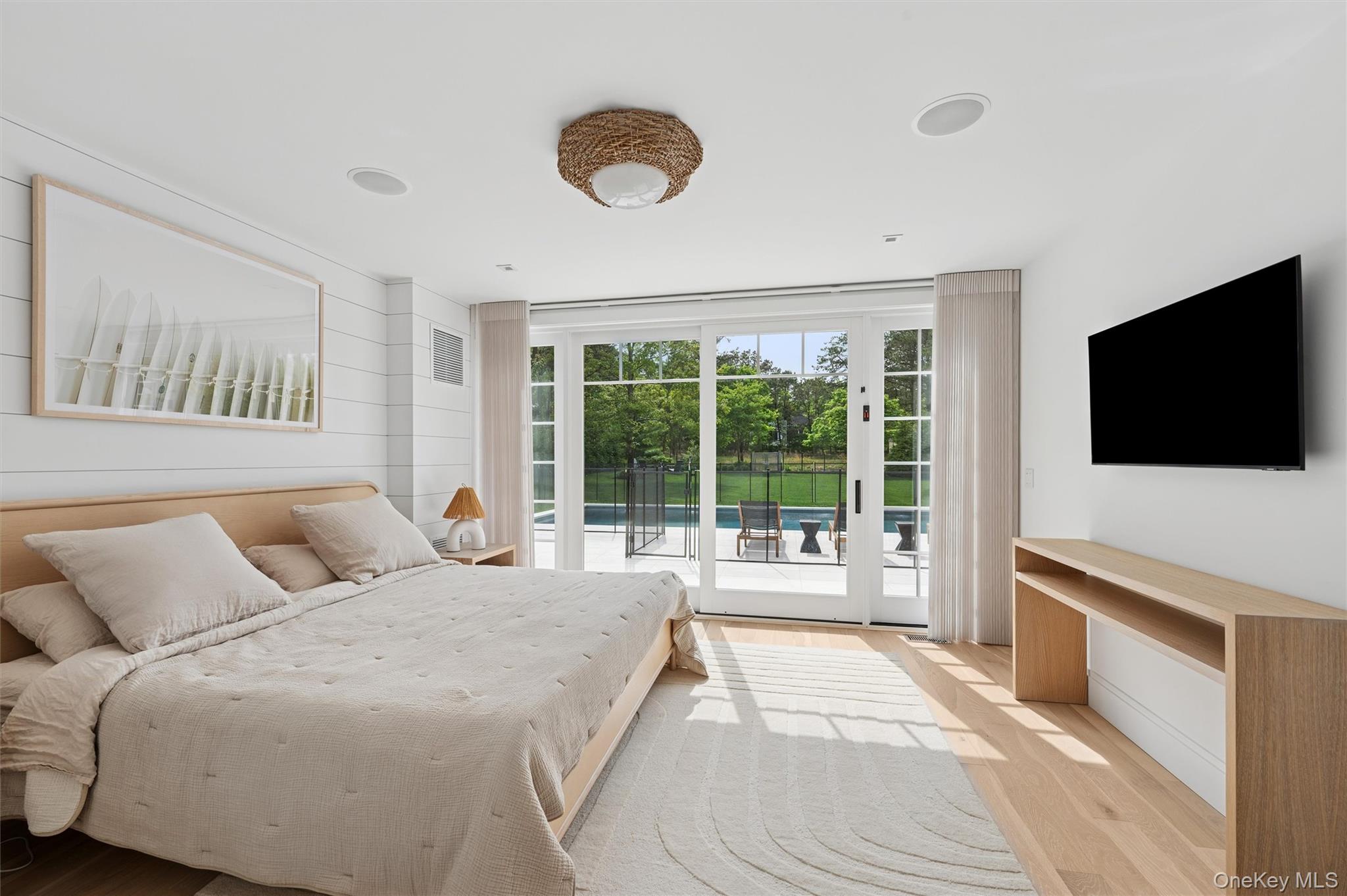 28 Canoe Place Road Hampton Bays, NY 11946 - Photo 13 of 34 a bedroom with a large bed and a flat tv screen on dresser