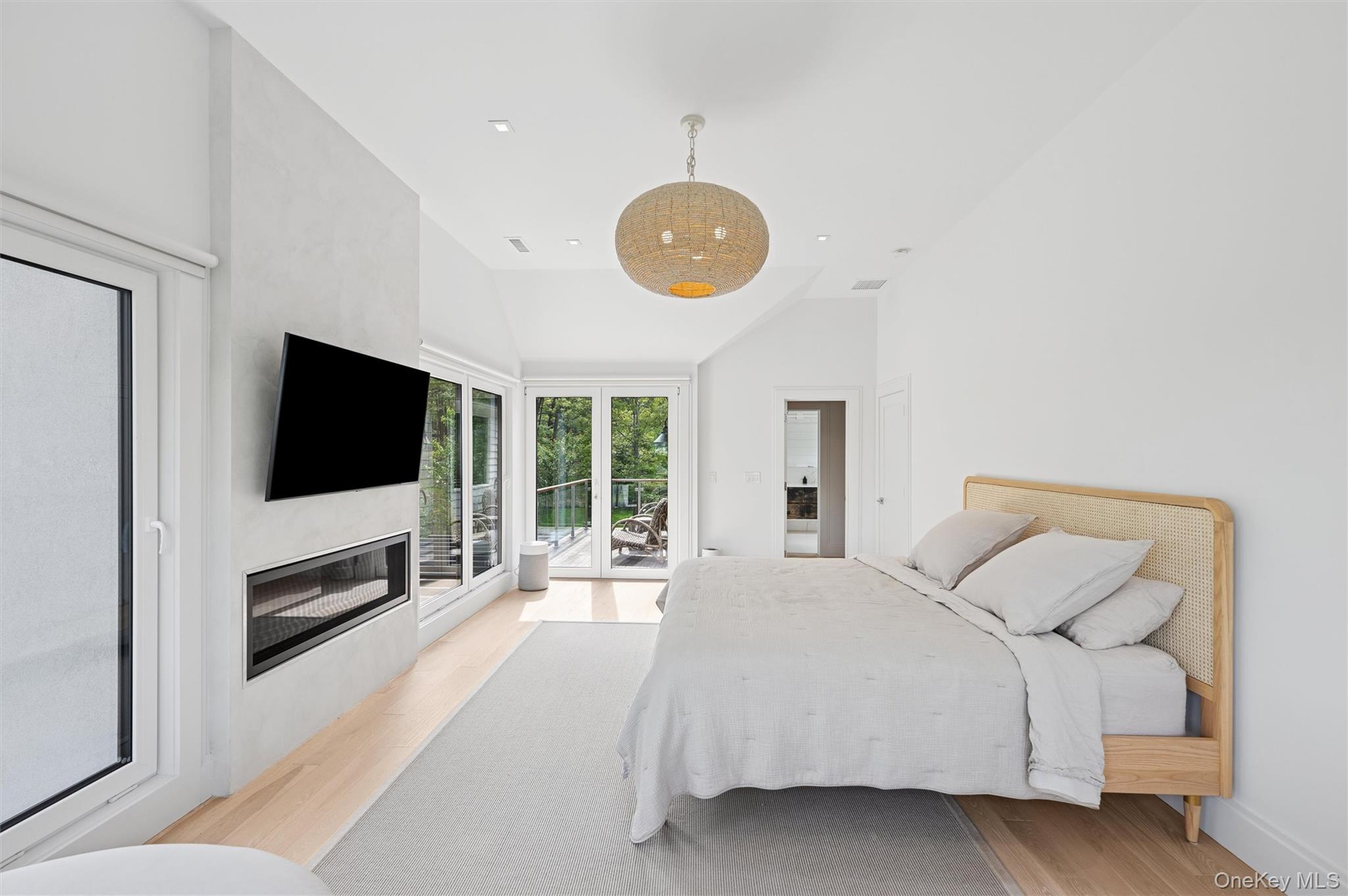 28 Canoe Place Road Hampton Bays, NY 11946 - Photo 18 of 34 a spacious bedroom with a bed and a flat screen tv