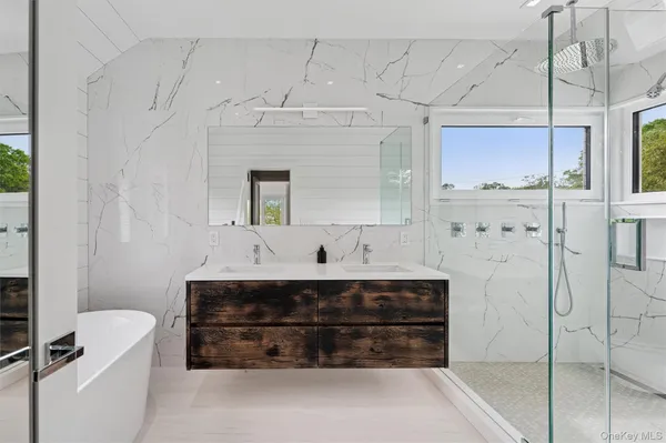 a bathroom with a double vanity sink a mirror and a bathtub