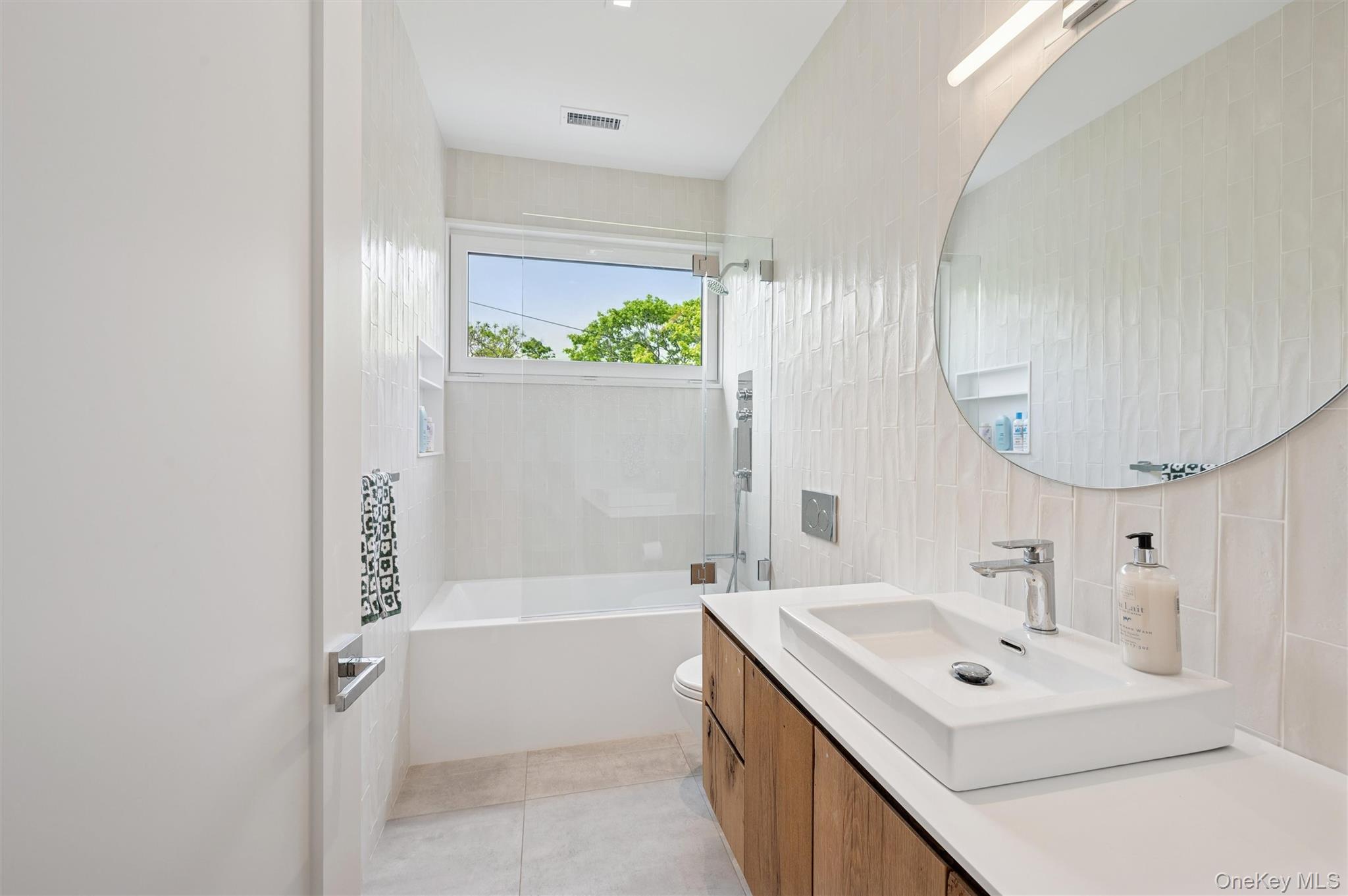 28 Canoe Place Road Hampton Bays, NY 11946 - Photo 23 of 34 a bathroom with a bathtub a sink and a mirror