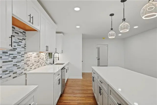 a kitchen with a sink and a stove with wooden floor