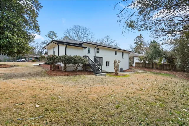 a view of a house with backyard and trees