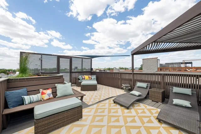 a roof deck with couches and sky view