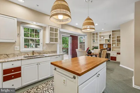 a kitchen with stainless steel appliances granite countertop a dining table chairs and a refrigerator