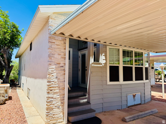 150 North 3050 East, Unit 4 St. George, UT 84790 - Photo 3 of 24 Exterior featuring light stucco siding, stacked stone accents, multiple large windows, and a covered entry