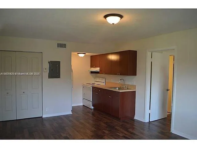 a living room with stainless steel appliances kitchen island a flat screen tv and a refrigerator