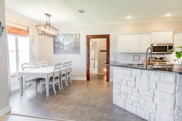 a kitchen with stainless steel appliances granite countertop a stove top oven a sink dishwasher and a dining table with wooden floor