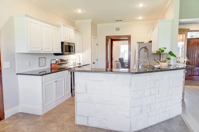 a kitchen with granite countertop a sink and white cabinets