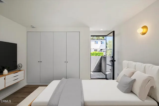 a bedroom with a bed and flat tv screen on the dresser