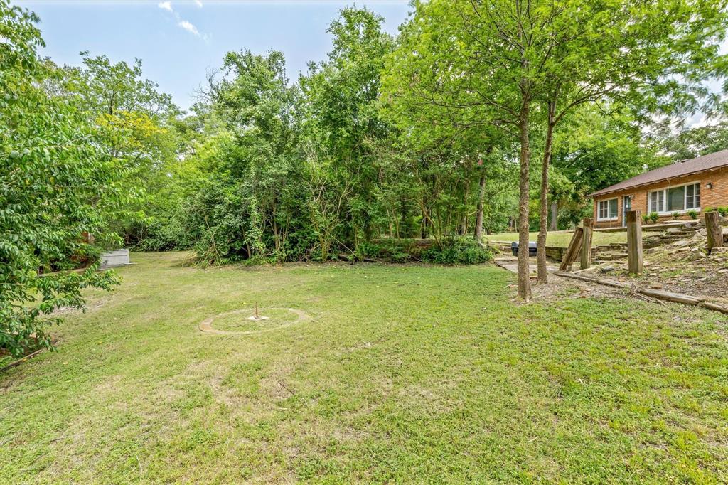 421 Rice Avenue Waco, TX 76708 - Photo 8 of 22 Expansive lawn area with mature trees, a brick exterior residence with multiple windows, and a tiered landscaped hillside