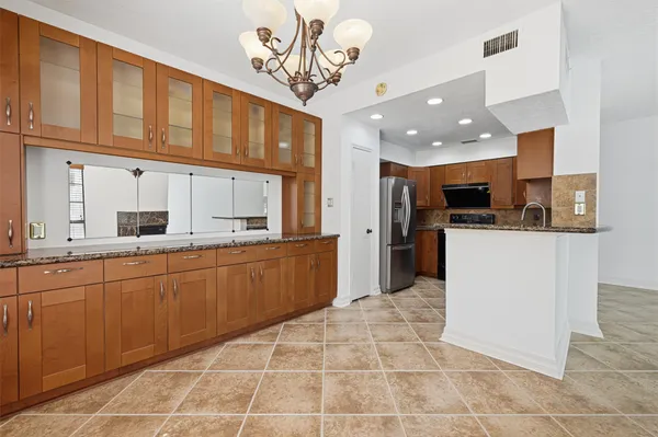 a large kitchen with stainless steel appliances kitchen island granite countertop a refrigerator a stove top oven and a sink with granite countertops