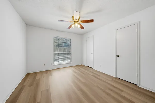 a view of empty room with wooden floor and fan