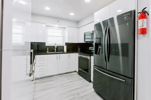 a kitchen with stainless steel appliances kitchen island a refrigerator sink and cabinets