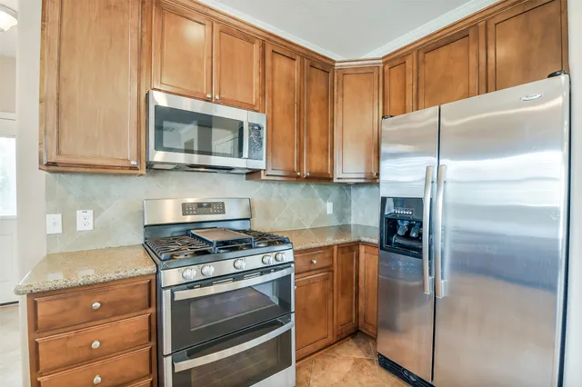 a kitchen with granite countertop a refrigerator stove and microwave