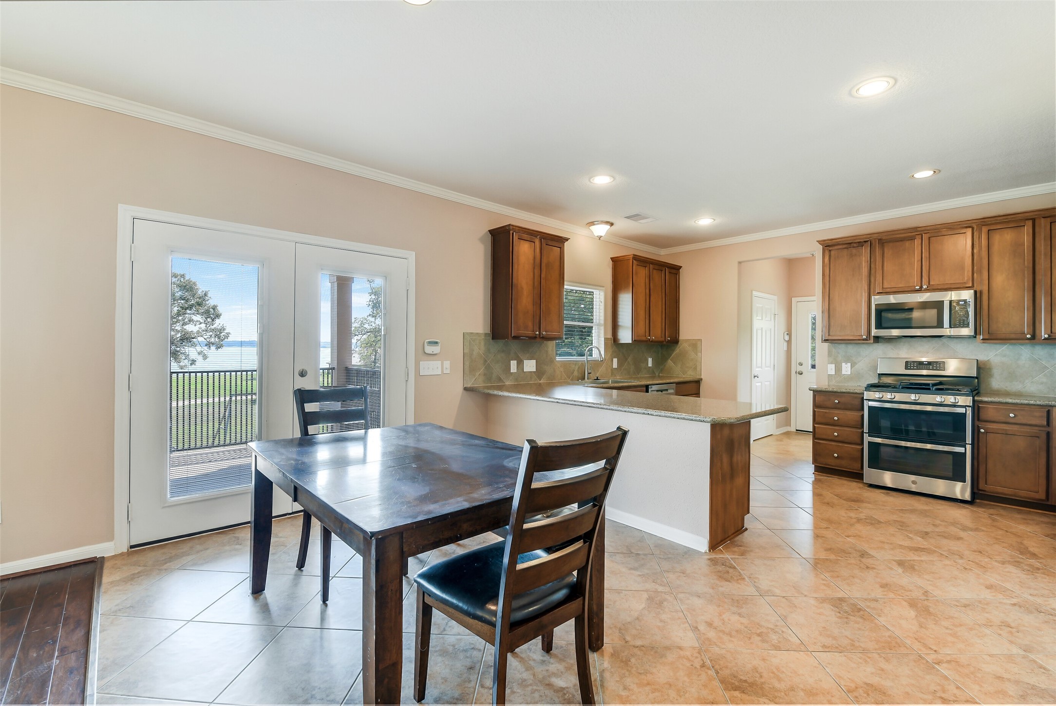 264 Falcon Point Onalaska, TX 77360 - Photo 7 of 33 a kitchen with granite countertop a stove top oven a sink dishwasher a dining table and chairs with wooden floor