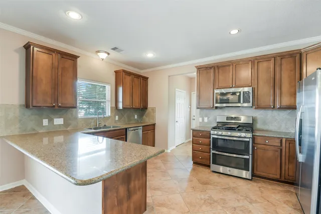 a kitchen with stainless steel appliances granite countertop a sink stove and refrigerator
