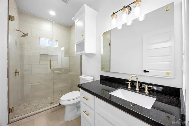a bathroom with a granite countertop sink toilet a mirror and shower