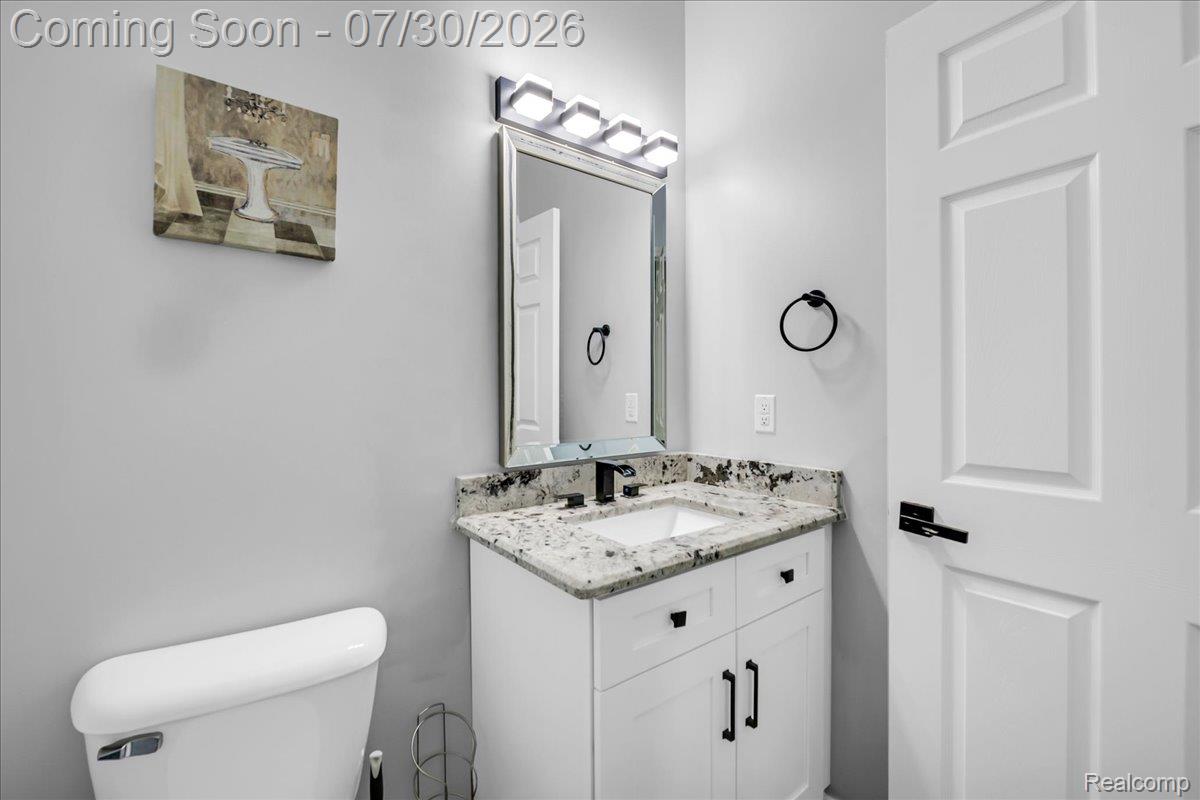 41447 Glade Road Canton, MI 48187 - Photo 14 of 28 Bathroom featuring a white vanity with granite countertop, integrated sink, and matte black faucet