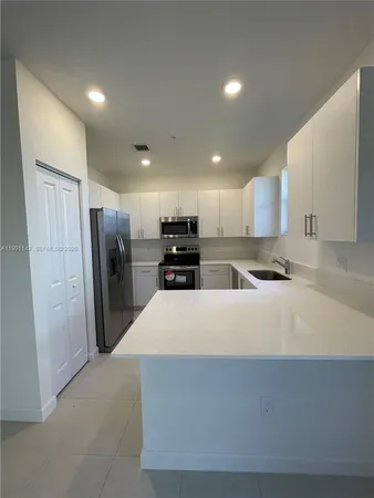 a large kitchen with stainless steel appliances a refrigerator and a stove top oven