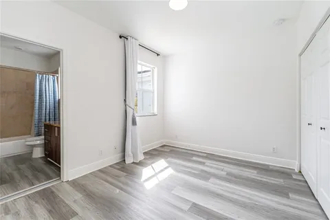 an empty room with wooden floor and a bathroom