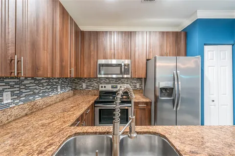 a kitchen with granite countertop a refrigerator and a stove top oven