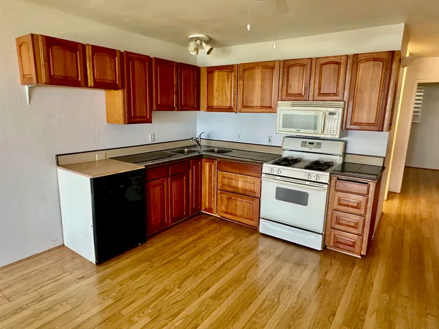 a kitchen with stainless steel appliances granite countertop a stove a sink dishwasher and a microwave oven with wooden floor