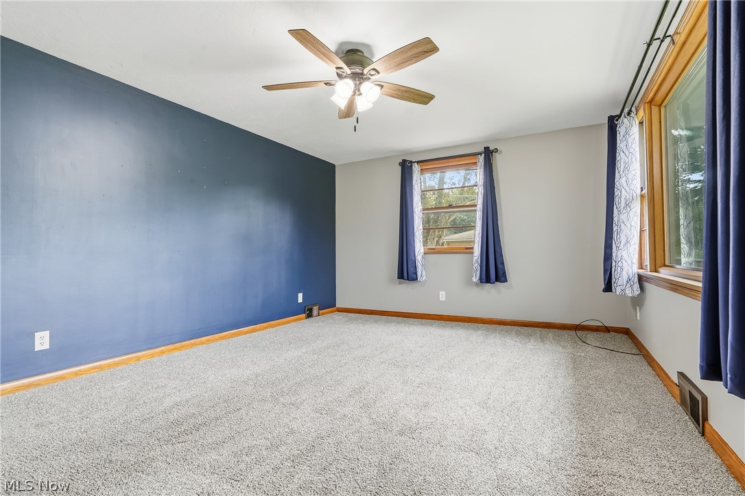 3633 Blacksnake Hill Road Northeast Dover, OH 44622 - Photo 9 of 38 Carpeted room featuring a ceiling fan with integrated lighting, wood-trimmed windows, and accent wall