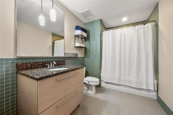 a bathroom with a granite countertop sink toilet and mirror