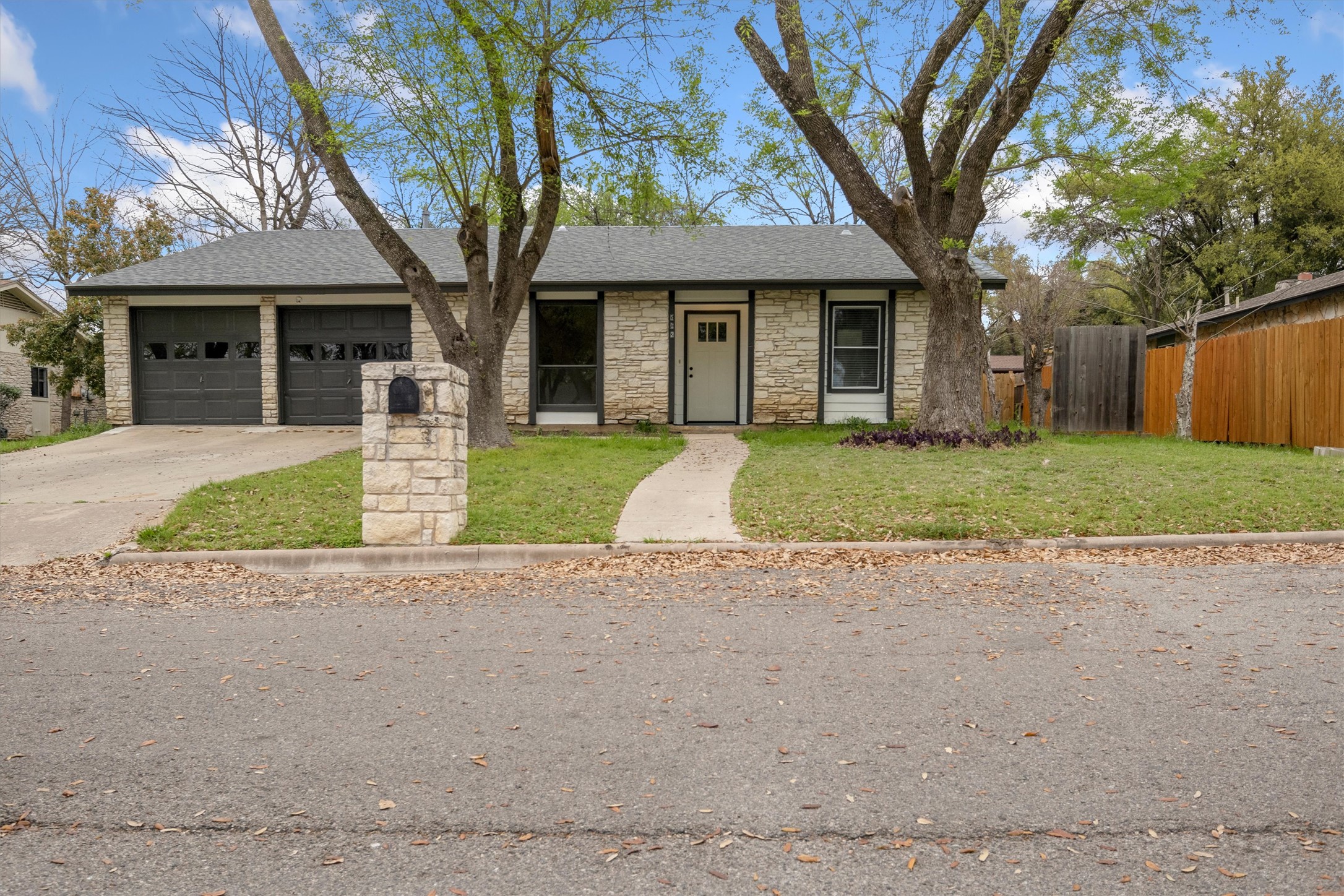 502 Pin Tail Lane Taylor, TX 76574 - Photo 24 of 26 Stone veneer exterior with dark-framed windows, a white entry door, and a two-car garage