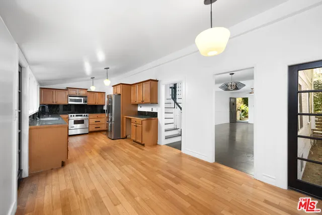 a kitchen with stainless steel appliances wooden floor and a large window
