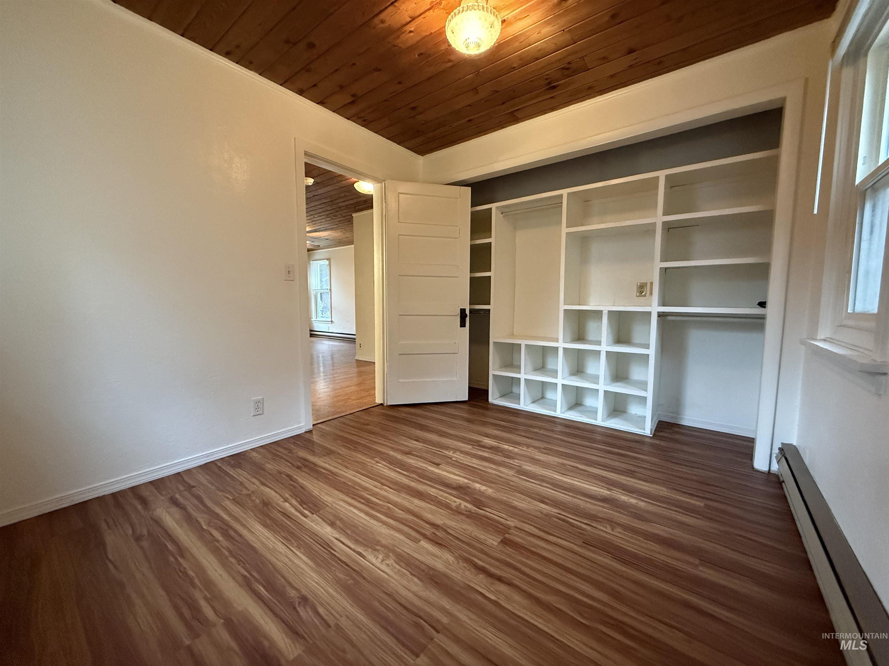 620 Riverside Avenue Orofino, ID 83544 - Photo 5 of 12 Empty room featuring baseboard heating, wooden ceiling, and dark wood-style flooring