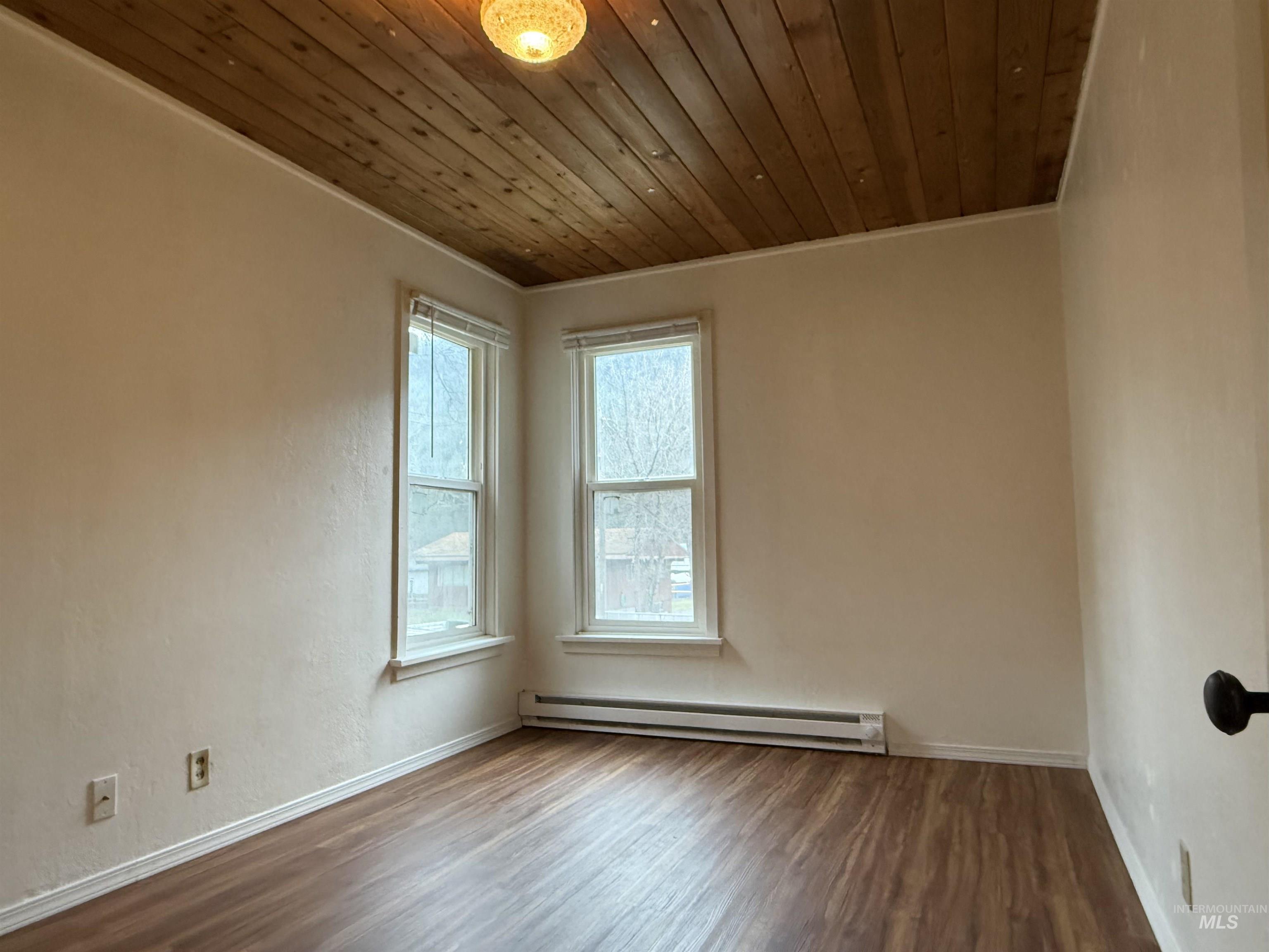 620 Riverside Avenue Orofino, ID 83544 - Photo 8 of 12 Unfurnished room featuring wooden ceiling, a baseboard radiator, wood finished floors, and ornamental molding