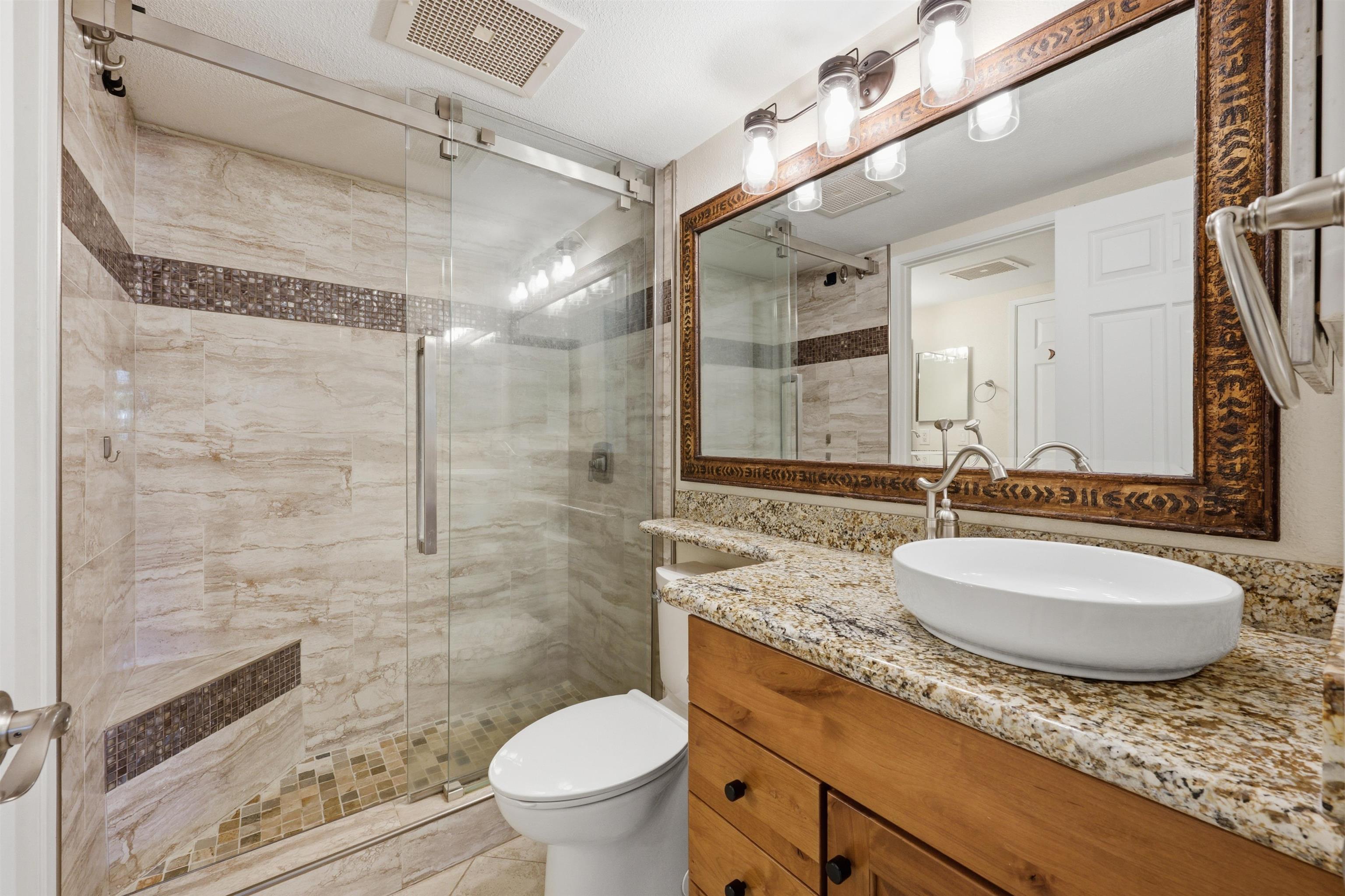 140 Uwapo Road, Unit 39101 Kihei, HI 96753 - Photo 19 of 35 a bathroom with a granite countertop sink toilet mirror and shower