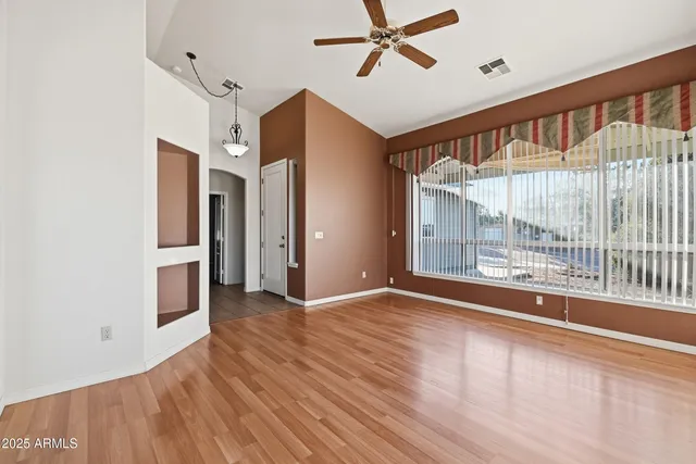 an empty room with wooden floor cabinet and a hallway