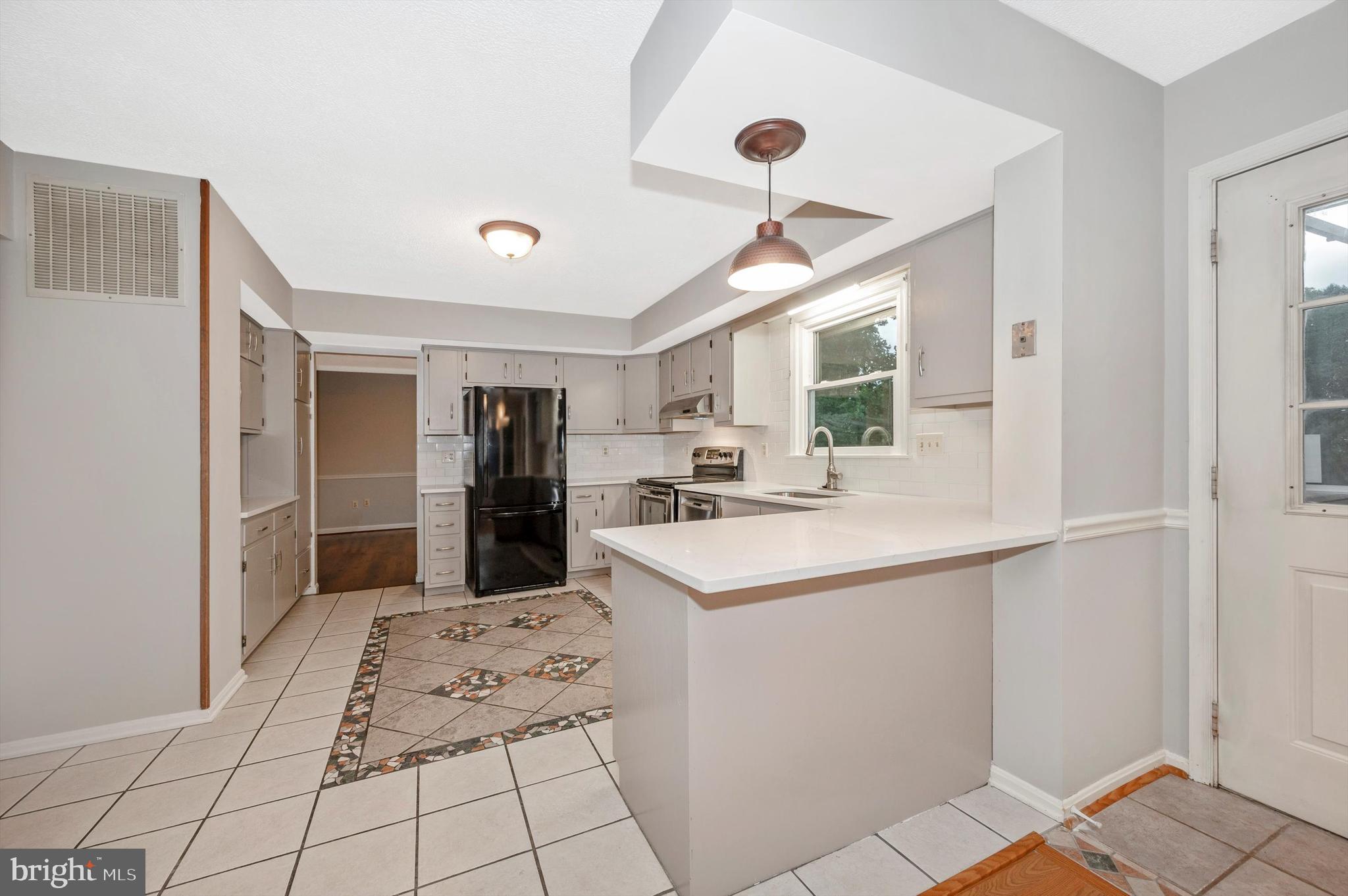 a kitchen with stainless steel appliances kitchen island granite countertop a refrigerator and a sink