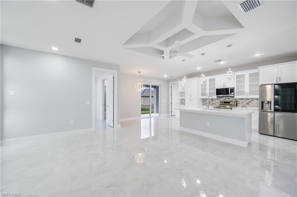 650 Kraft Street Lehigh Acres, FL 33974 - Photo 7 of 29 a large white kitchen with white cabinets and stainless steel appliances