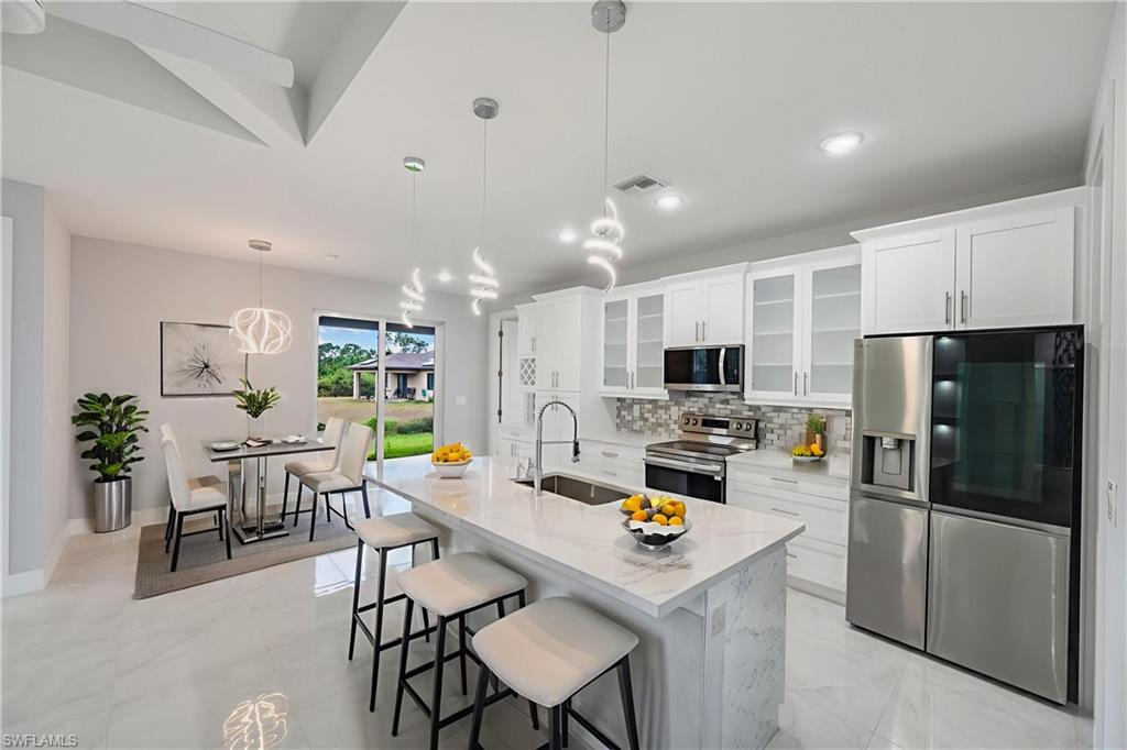 650 Kraft Street Lehigh Acres, FL 33974 - Photo 9 of 29 a kitchen with a dining table chairs refrigerator and microwave