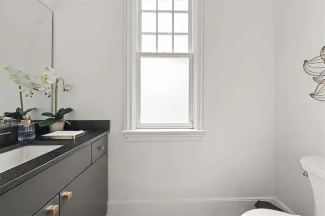a bathroom with a granite countertop sink and a toilet