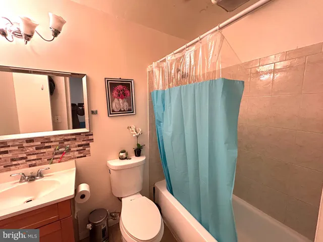 a bathroom with a sink a toilet a shower curtain and a large mirror