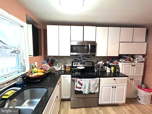 a kitchen with granite countertop a stove a sink and a granite counter tops with white cabinets