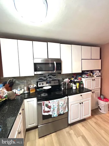 a kitchen with stainless steel appliances a stove top oven a sink a counter space and cabinets