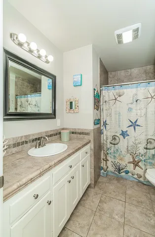 a bathroom with a granite countertop sink mirror and a shower