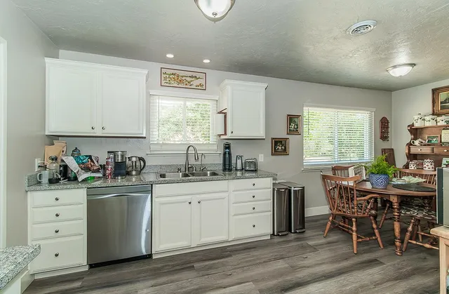 a kitchen with stainless steel appliances a stove a sink a window and dining table