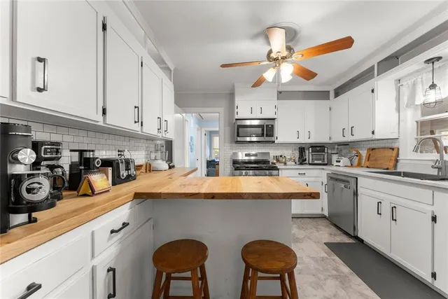 a kitchen with stainless steel appliances a sink a stove a refrigerator cabinets and a window