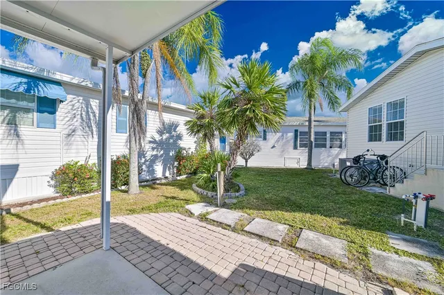 a view of a house with a yard and palm trees