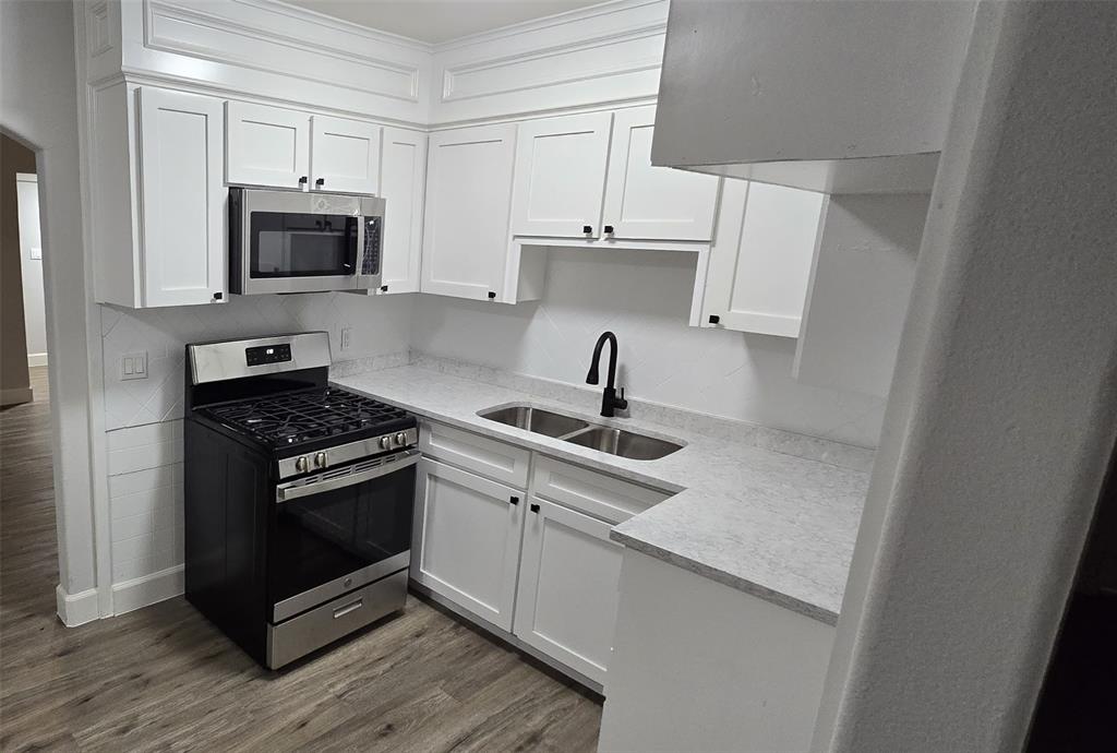 405 Southwest 6th Street Grand Prairie, TX 75051 - Photo 5 of 16 Kitchen featuring stainless steel appliances, dark wood finished floors, white cabinets, and light stone counters