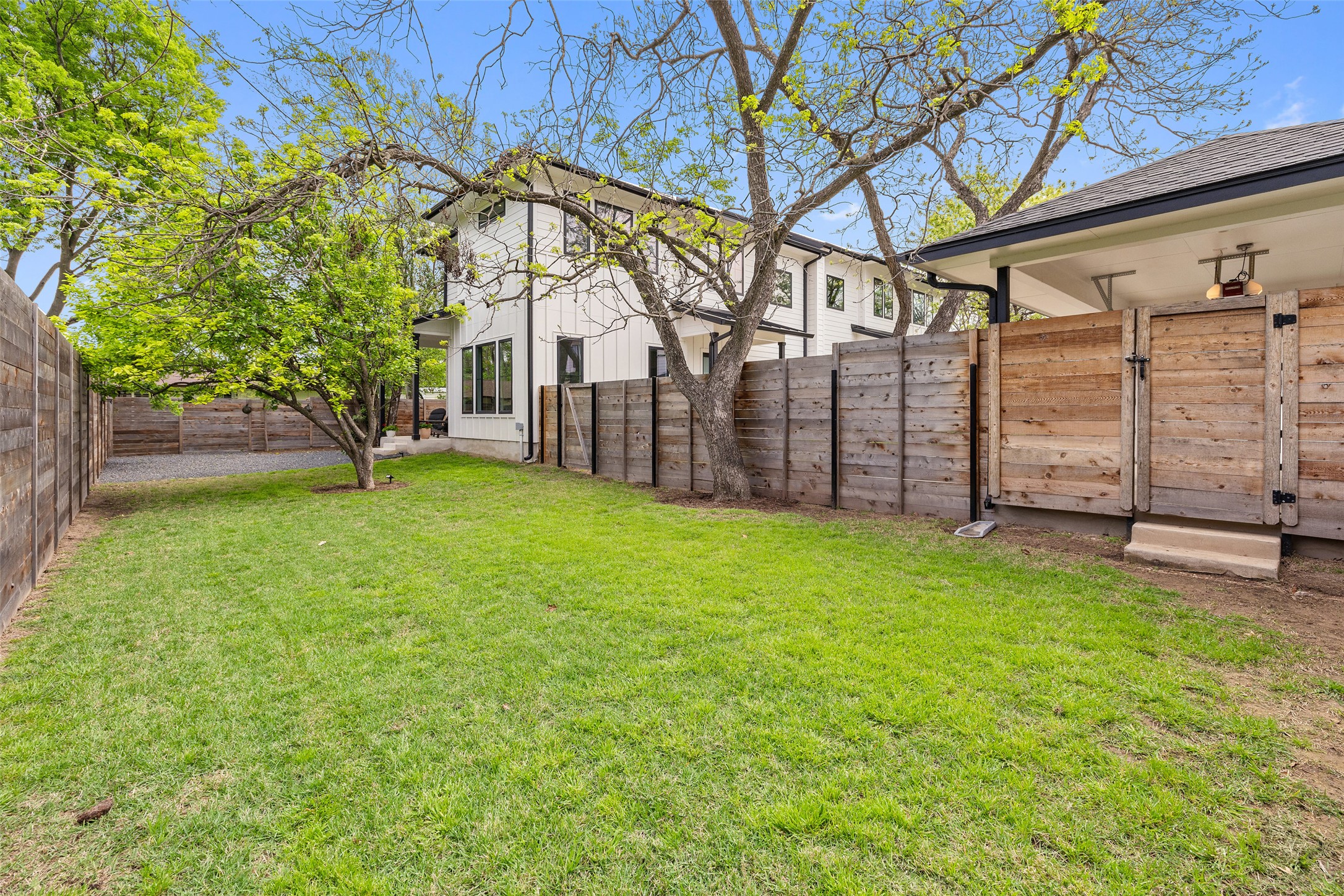 1504 Ruth Avenue, Unit 3 Austin, TX 78757 - Photo 36 of 39 A verdant lawn graces the side yard, enclosed by a robust wooden privacy fence, offering a tranquil outdoor retreat.