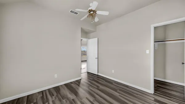 a view of a room with wooden floor and a ceiling fan